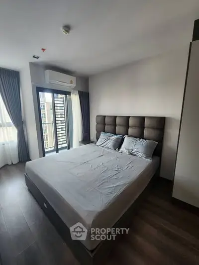 Modern bedroom with large window and balcony access in a stylish apartment.