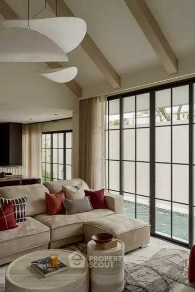 Luxurious living room with modern decor and pool view, featuring elegant furniture and large windows.