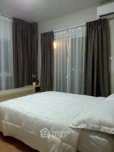 Cozy bedroom with elegant curtains and comfortable bedding in modern apartment.