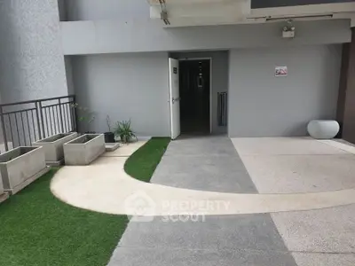 Modern apartment building entrance with stylish walkway and planters.