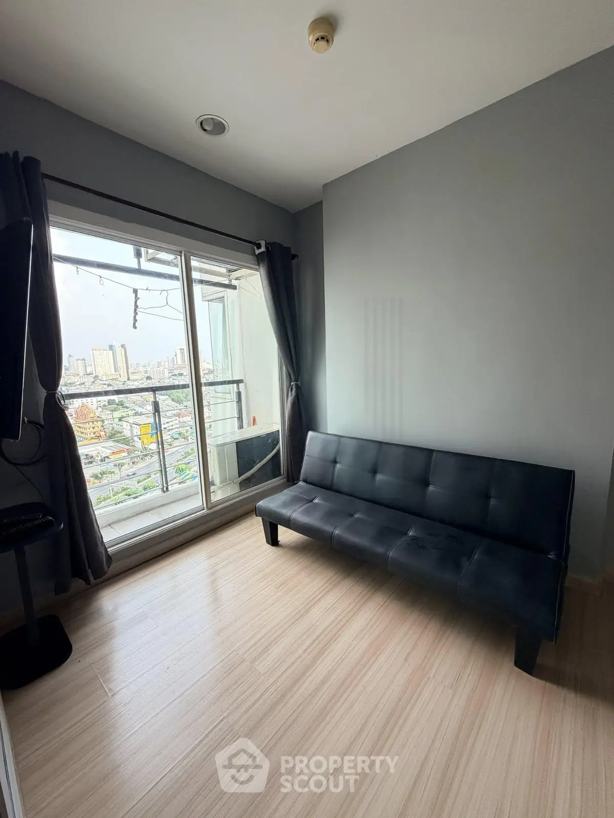 Modern living room with sleek black sofa and city view from balcony