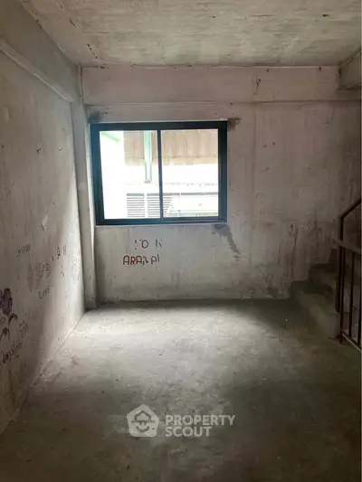 Unfinished room with concrete walls and window, potential for customization.