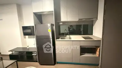 Modern compact kitchen with sleek cabinetry and stainless steel appliances in a stylish apartment.