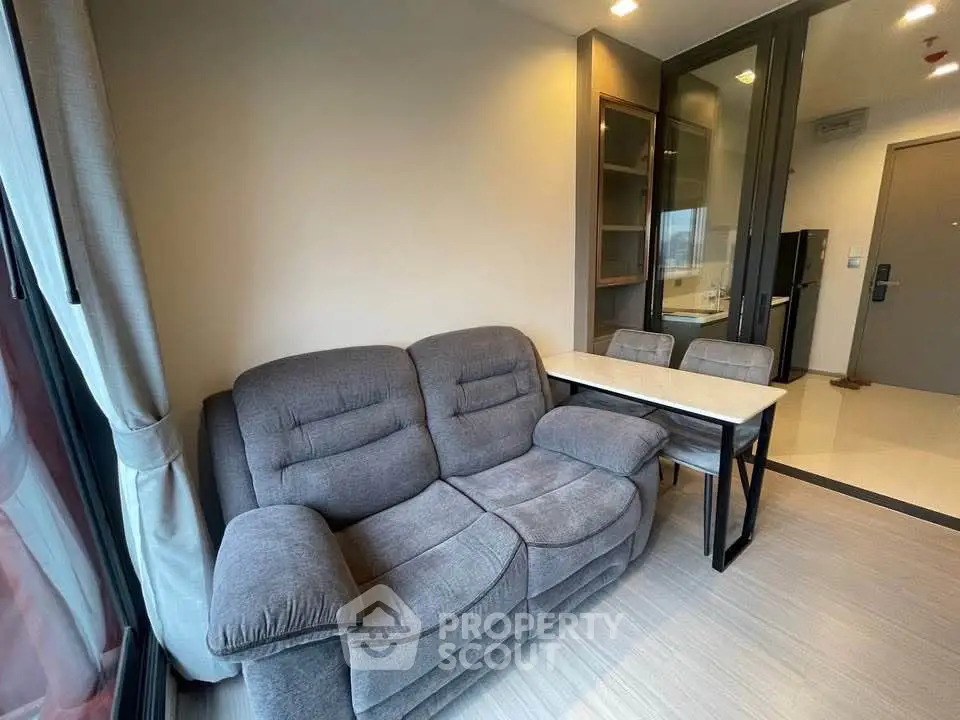 Cozy living room with plush gray sofa and modern dining area in stylish apartment.