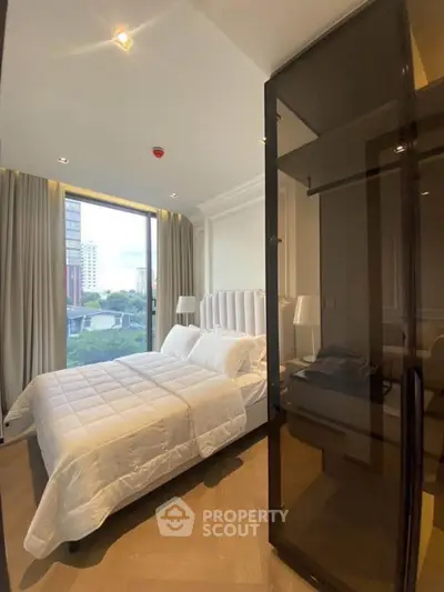 Luxurious bedroom with large window offering stunning city views, elegant decor, and plush bedding.