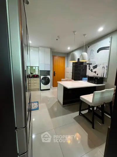 Modern kitchen with sleek design, featuring a washing machine and stylish lighting.