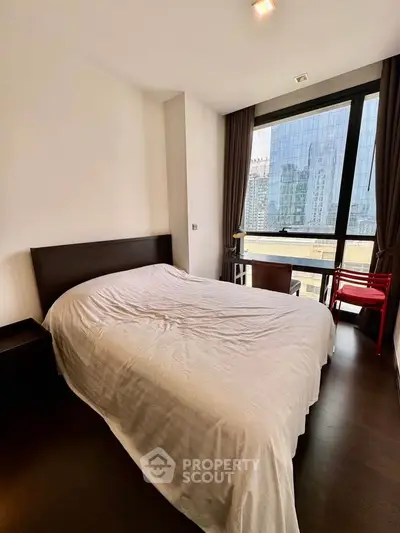 Modern bedroom with city view and elegant furnishings in high-rise apartment.