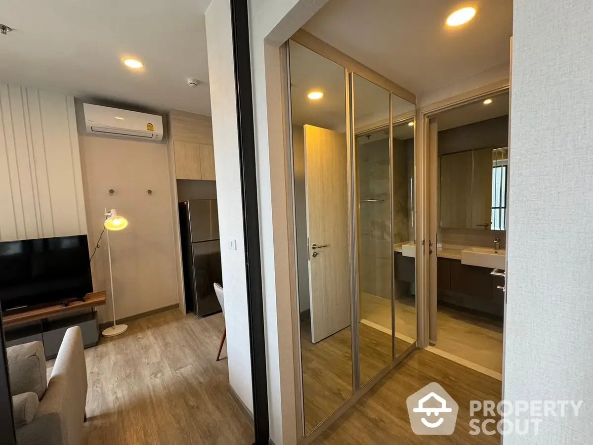 Modern apartment interior showcasing a cozy living room with sleek furniture and a glass partition leading to a sophisticated bathroom.