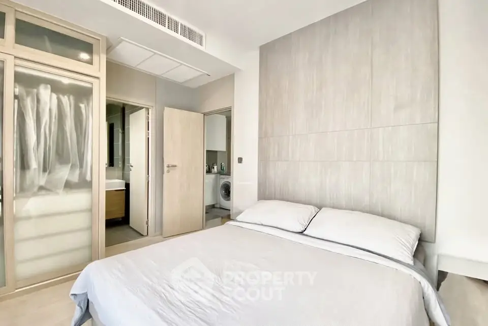 Modern bedroom with ensuite bathroom and laundry area, featuring sleek design and neutral tones.