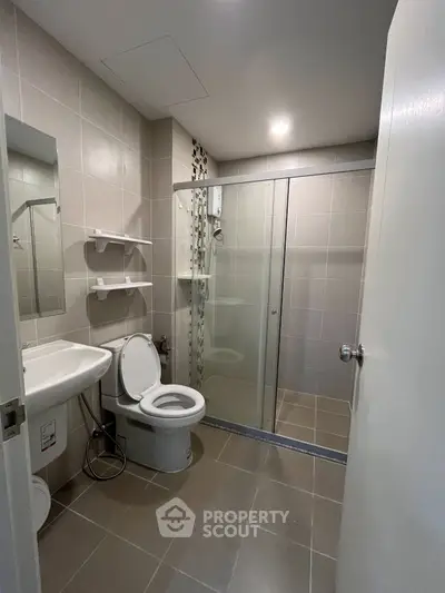Modern bathroom with glass shower and sleek fixtures in contemporary apartment.