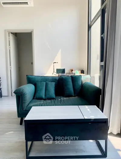 Stylish living room with modern teal sofa and sleek coffee table, bathed in natural light from large windows.