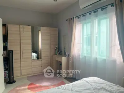 Cozy bedroom with modern wardrobe and natural light through large window.