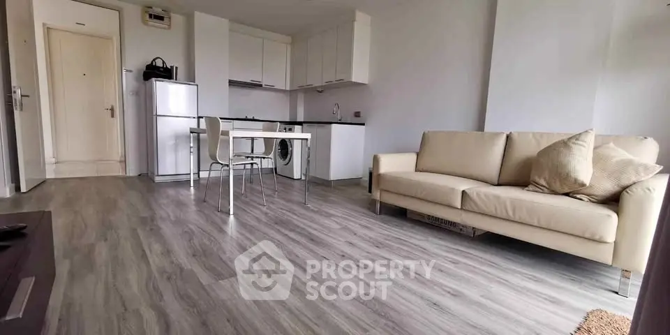 Modern open-plan living room with kitchen, featuring sleek flooring and neutral decor.