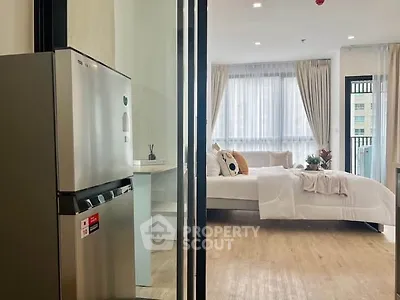 Modern apartment interior with open layout, featuring a cozy bedroom and sleek kitchen area.