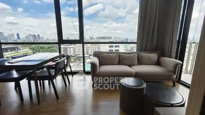 Spacious living room with stunning city view and modern furniture in high-rise apartment.
