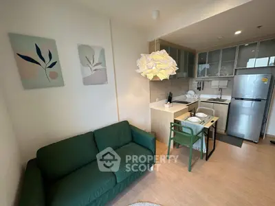 Modern living room with green sofa and stylish kitchen in open layout apartment.