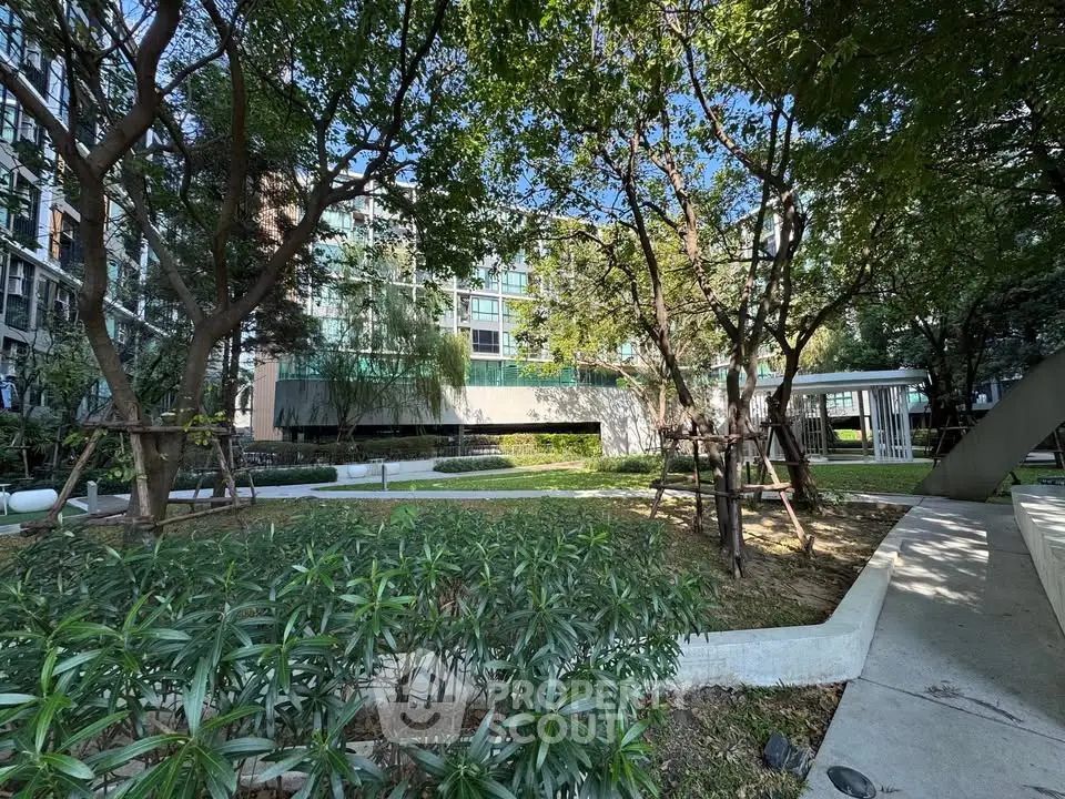 Lush garden view of modern apartment complex with mature trees and landscaped pathways.