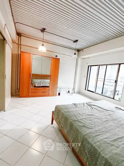 Spacious bedroom with large windows and modern wardrobe in urban apartment