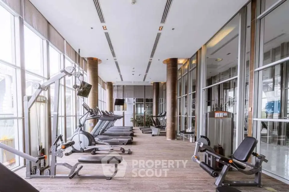 Spacious modern gym with state-of-the-art equipment and floor-to-ceiling windows.