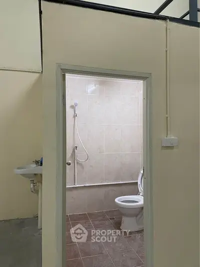 Compact bathroom with shower and toilet in a minimalist setting.
