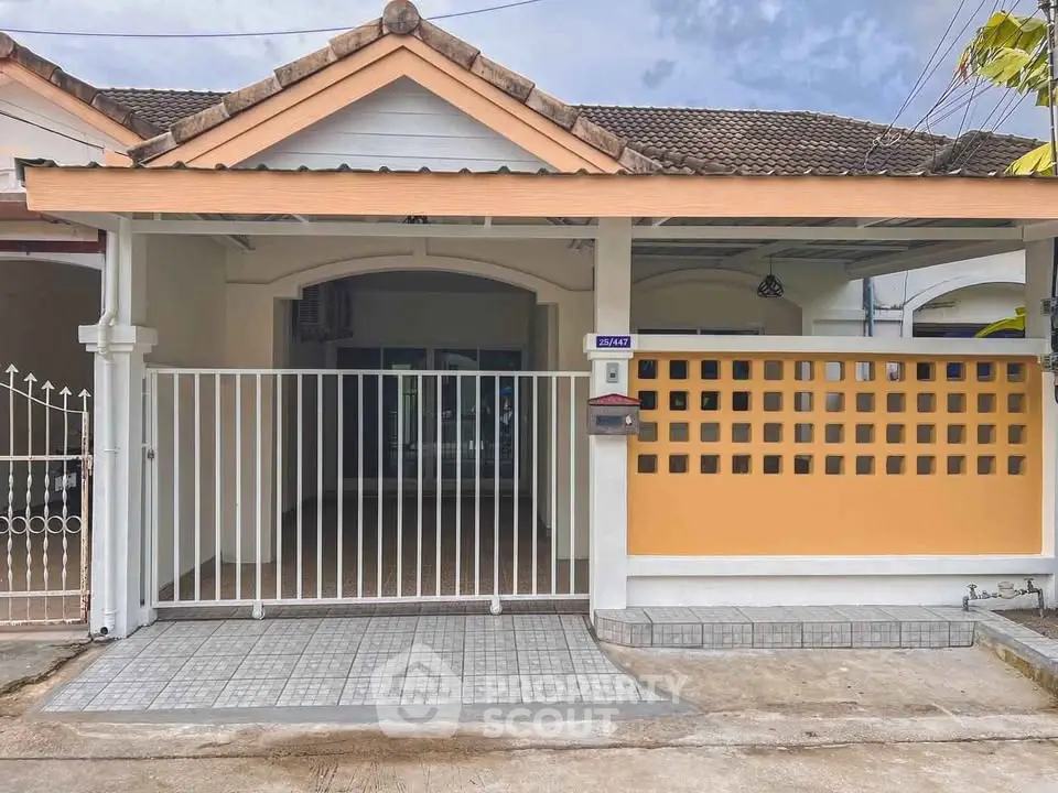 Charming single-story house with gated entrance and tiled driveway in a peaceful neighborhood.