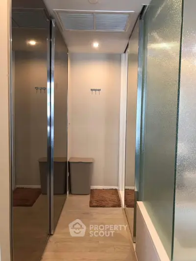Modern hallway with mirrored closets and wooden flooring in a stylish apartment.