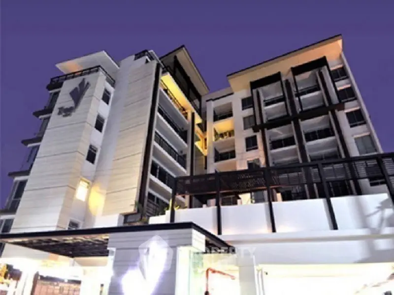 Modern multi-story residential building with contemporary architecture against a twilight sky.