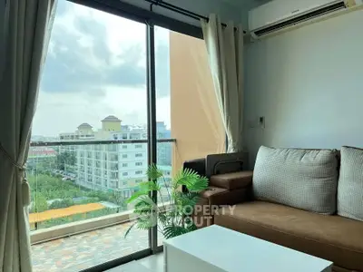 Modern living room with large windows offering a stunning city view, cozy sofa, and air conditioning.