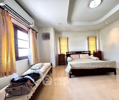Spacious bedroom with natural light, featuring a large bed and cozy decor, perfect for relaxation.