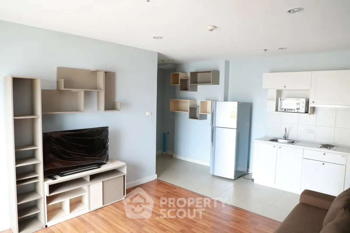 Modern living room with open kitchen and stylish shelving in a cozy apartment.