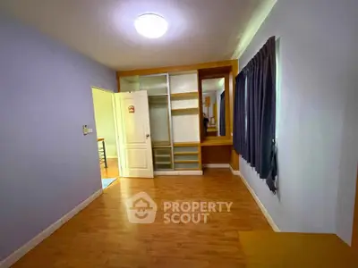 Spacious bedroom with wooden flooring and built-in wardrobe in modern apartment.