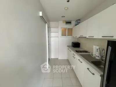 Modern kitchen with sleek white cabinets and stainless steel appliances in a compact layout.