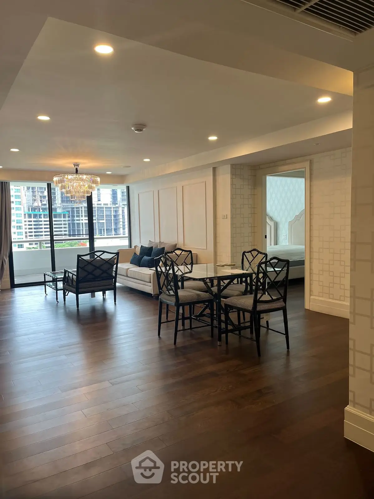 Spacious living room with elegant decor and city view, featuring hardwood floors and modern furniture.