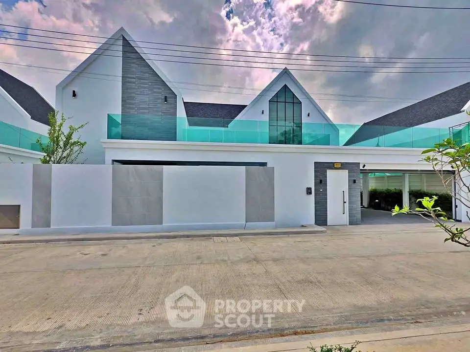 Modern luxury home with sleek design and large glass windows, featuring a spacious driveway.