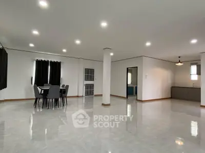 Spacious open-plan living and dining area with modern lighting and sleek tile flooring.