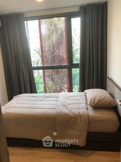 Cozy bedroom with large window and garden view, featuring modern decor and natural light.