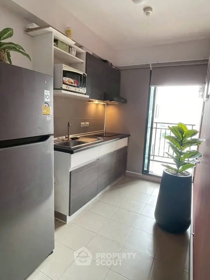 Modern kitchen with sleek cabinetry and balcony access for natural light.