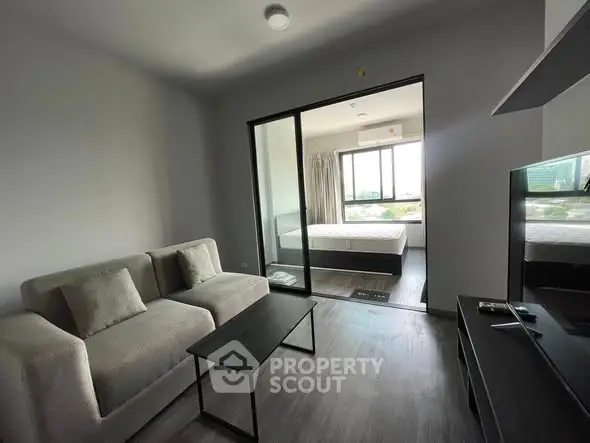 Modern living room with sleek furniture and a view into a cozy bedroom