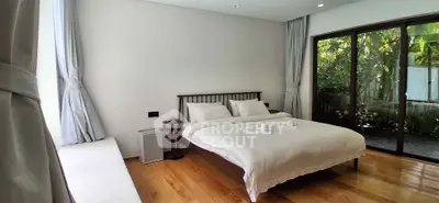 Spacious bedroom with large windows and garden view, featuring elegant wooden flooring and modern decor.