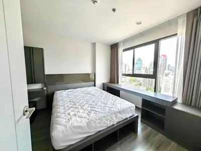 Modern bedroom with city view, featuring sleek furniture and large windows for natural light.