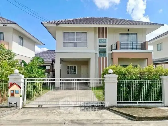 Charming two-story house with gated driveway and lush greenery in a serene neighborhood.