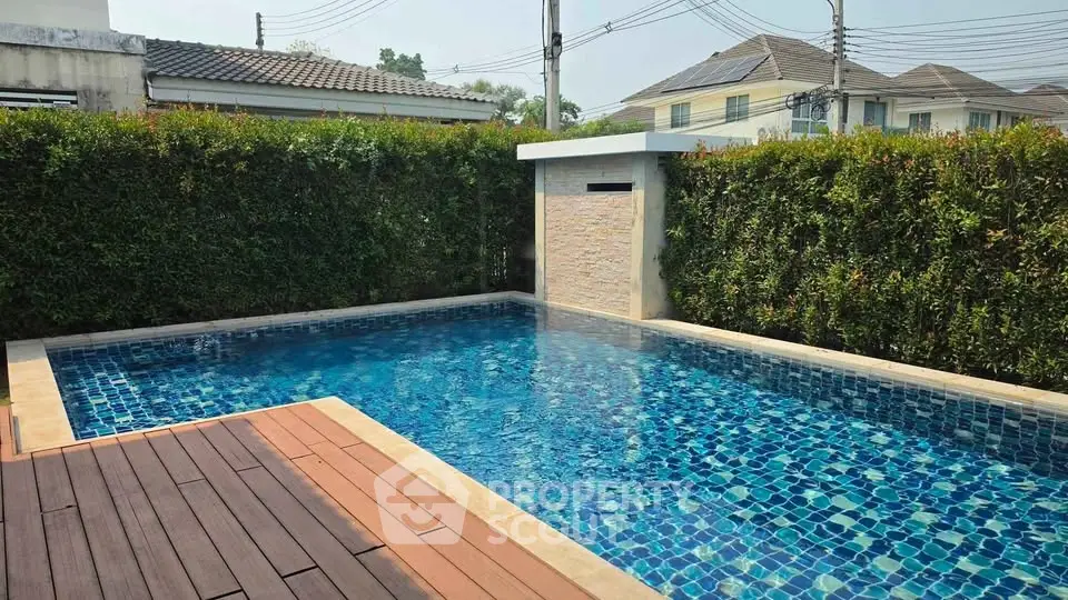 Luxurious private pool with elegant wooden deck in serene residential area.