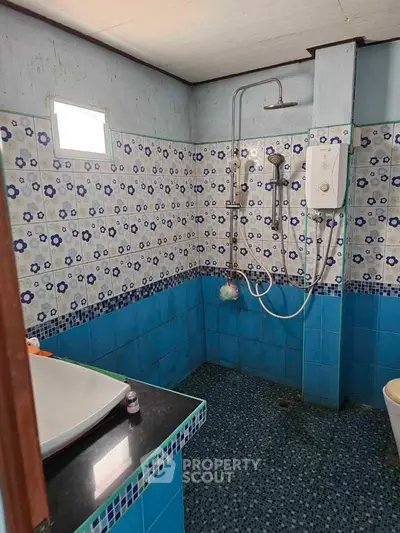 Charming vintage bathroom with floral tiles and modern shower fixtures.