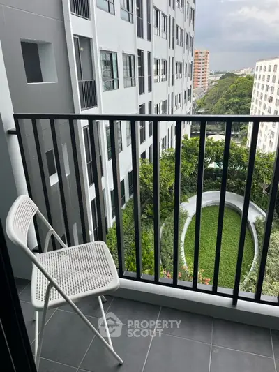 Modern balcony with city view and garden below, featuring sleek railing and minimalist chair.