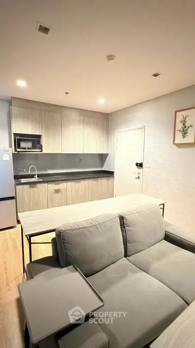 Modern open-layout kitchen and living room with sleek cabinetry and cozy seating area.