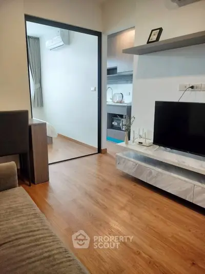 Modern apartment interior with open living room and kitchen, featuring sleek wooden flooring and contemporary decor.