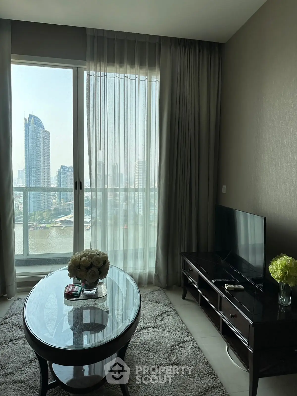 Elegant living room with river view, modern furniture, and large windows in a high-rise apartment.