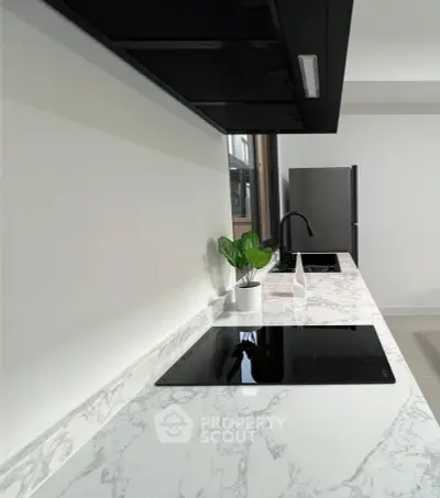 Modern kitchen with sleek marble countertops and built-in electric stove, featuring minimalist design and stainless steel appliances.