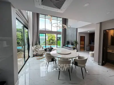 Luxurious open-plan living room with pool view, high ceilings, and elegant decor.