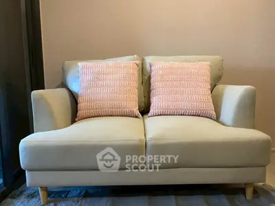 Cozy living room with stylish beige sofa and pink cushions, perfect for relaxation and modern decor.